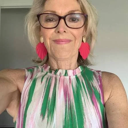 Portrait of a smiling mature woman with pink earrings, representing real consumer satisfaction with bladder control relief.