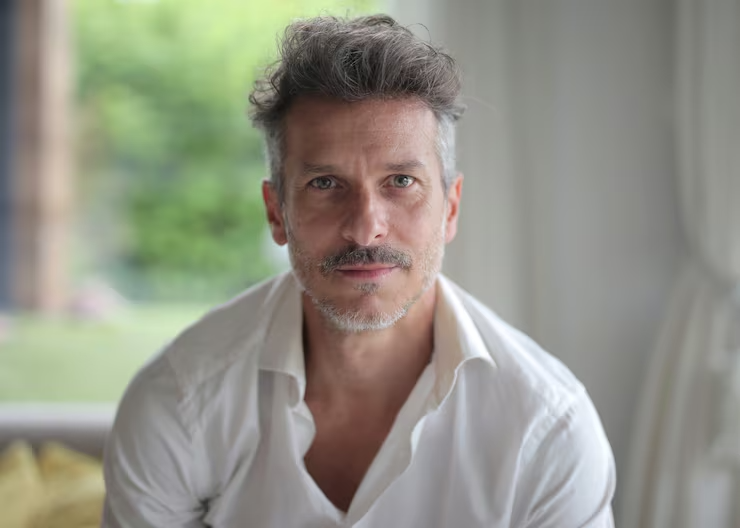 Headshot portrait of a confident mature man wearing a white shirt, illustrating restored vitality and energy.
