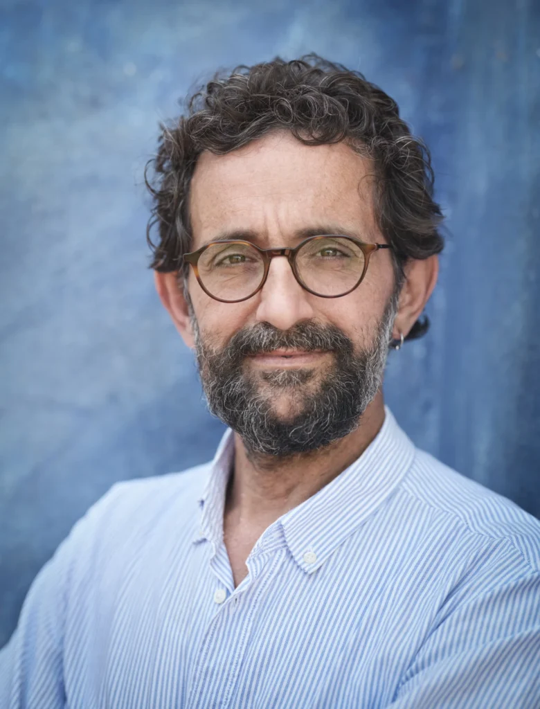 Portrait of a smiling middle-aged man with glasses and curly dark hair, representing real consumer trust.